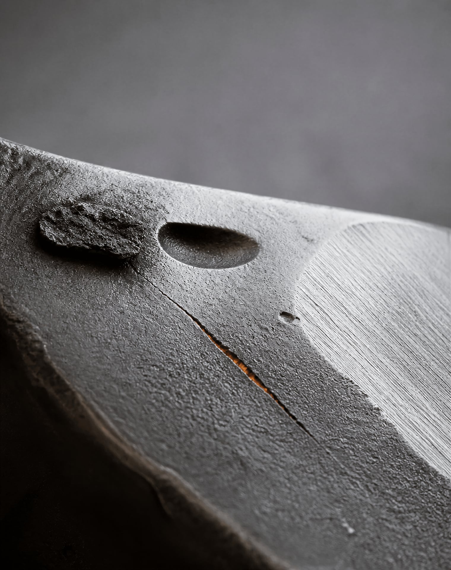 Close view of a steel casting surface with a crack-like line, cavity, molding residue, and grinding mark.