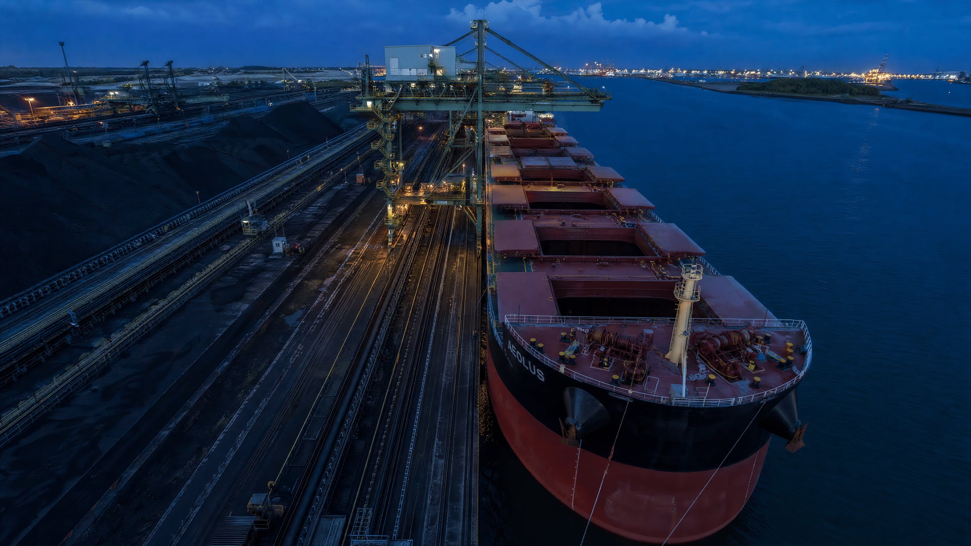 Bulk carrier loading Australian coking coal beside stockpiles at a seaborne terminal