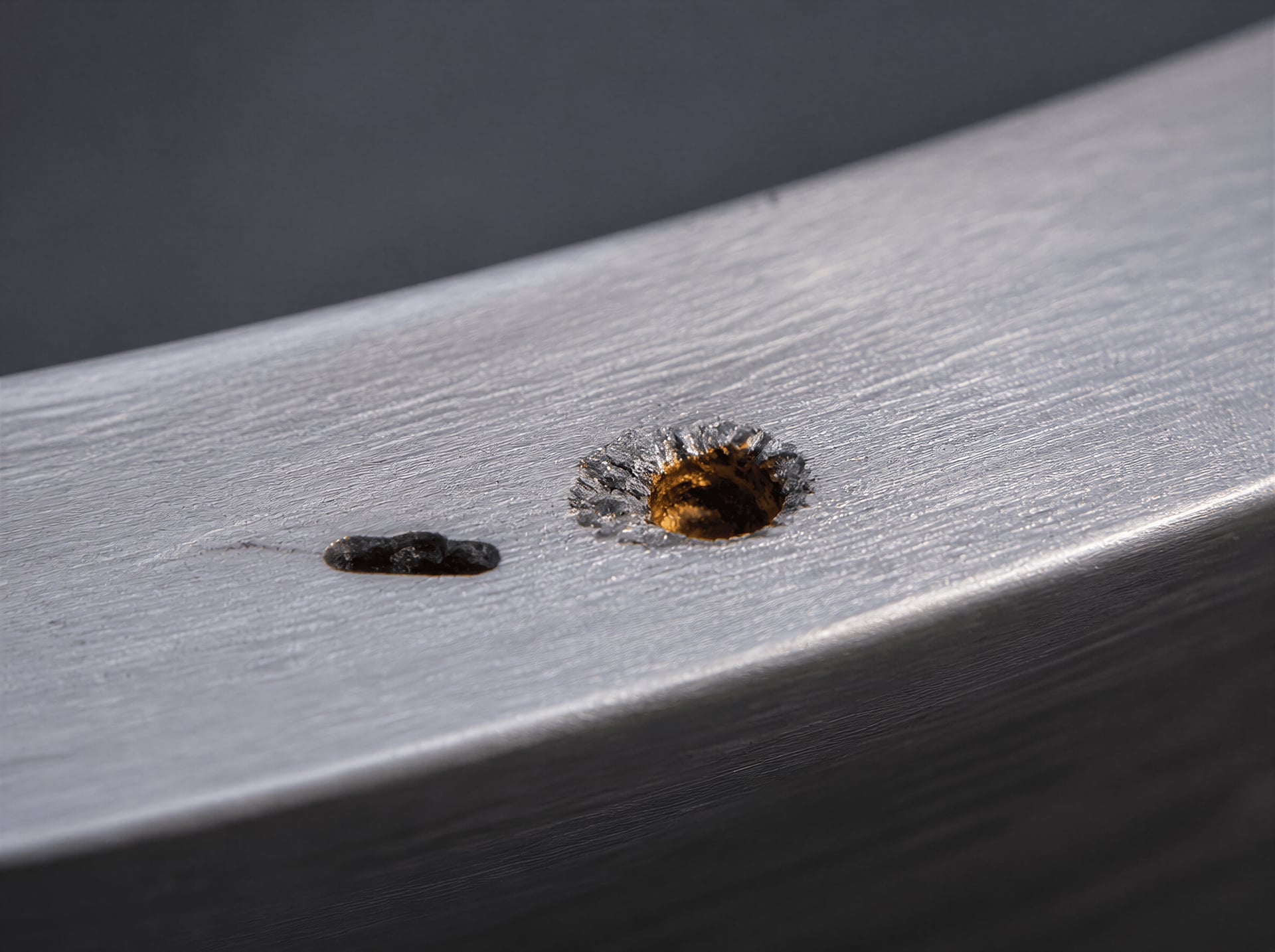 Manganese sulfide inclusion beside a small corrosion pit on stainless steel.