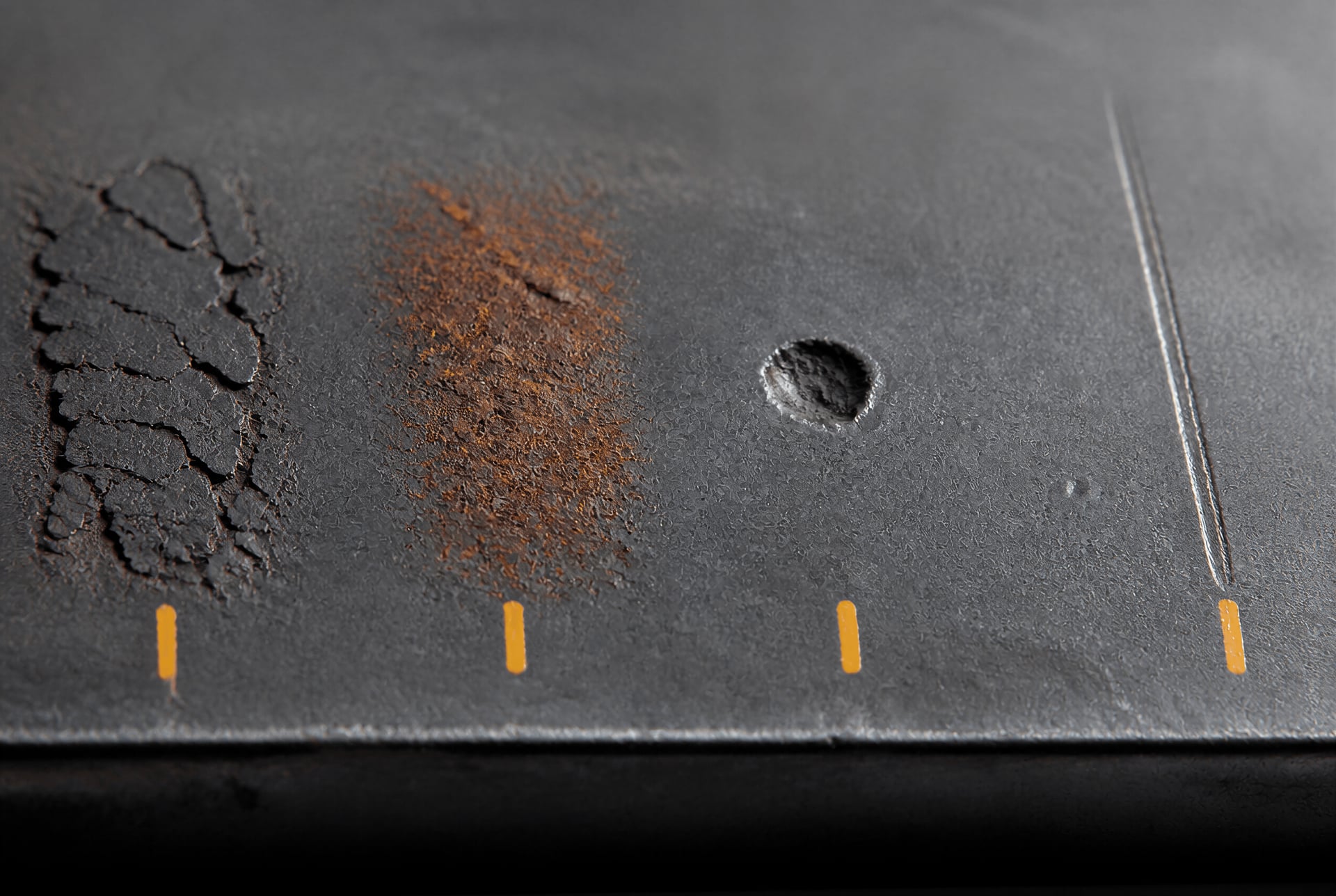 Macro view of mill scale, rust, a pit, and a seam on steel