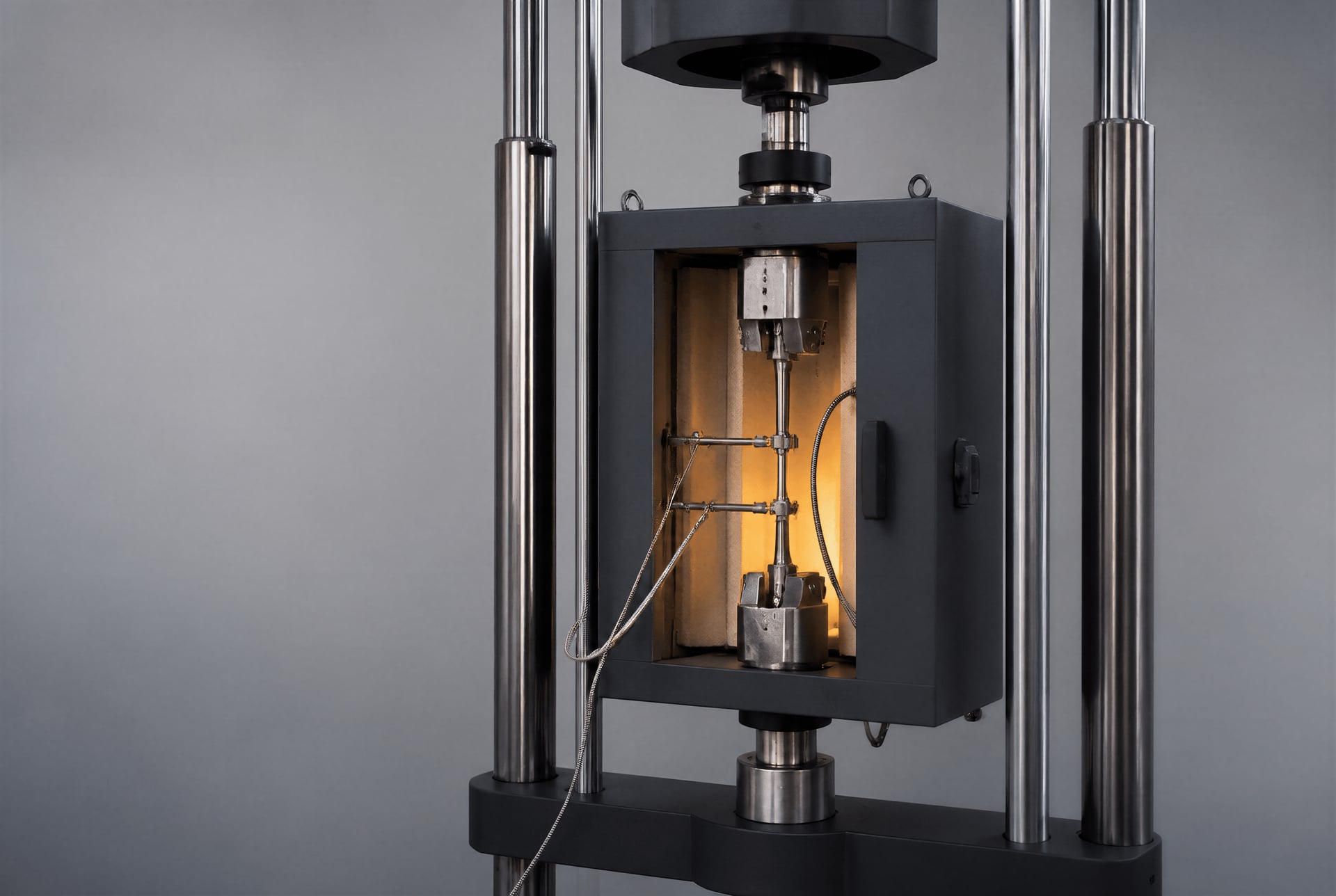 Creep-testing machine with a steel specimen, extensometer, and thermocouples